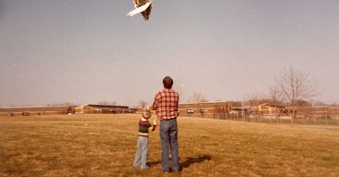A father and a son flying a kite together on a field
