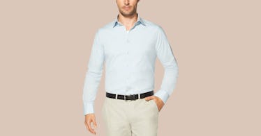 A man wearing a light blue shirt tucked in his beige pants with a black belt with a light orange bac...