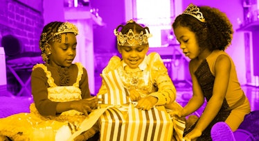 two girls at a kids birthday party watch the 5-year-old birthday girl open a gift