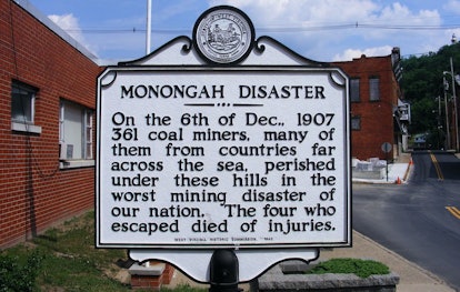A black and white memorial table sign on the street about the Monongah Disaster
