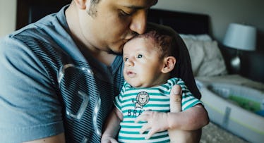 close up of a father kissing a baby on the forehead