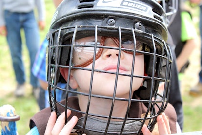 A little boy wearing a black hockey helmet with face protection