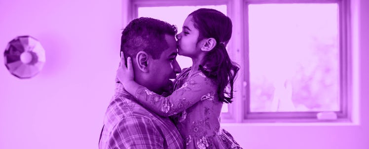 A daughter kissing her father on the forehead