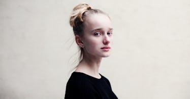 A sad teenage girl stares at the camera.