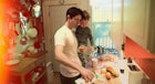 A dad in the kitchen preparing a meal while holding his toddler in his arms
