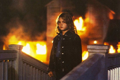 A scene from 'Firestarter' with a child standing in front of a burning house 