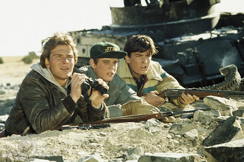 A scene from 'Red Dawn' with three male characters holding guns and looking through binoculars 