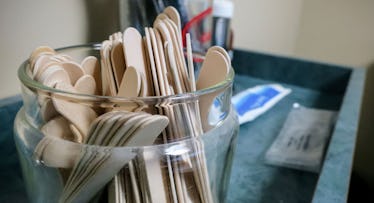 A glass jar filled with wooden spatula's at a doctor's office