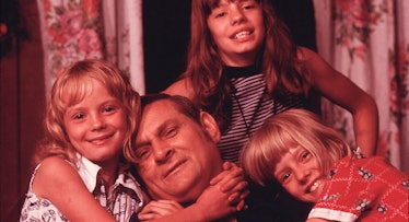 A father and his three daughters hugging and smiling