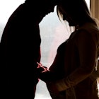 silhouette of a man placing a hand on the baby bump of his pregnant wife