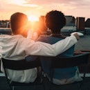 Couple sitting in an embrace on a rooftop looking at the sunset after reading marriage advice.