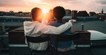 Couple sitting in an embrace on a rooftop looking at the sunset after reading marriage advice.