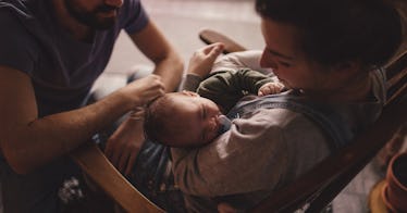 Woman holding baby with partner nearby.