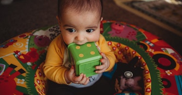 Baby chewing on a large toy block.