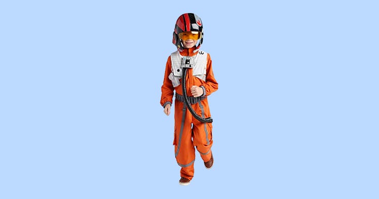 a boy dressed as Poe Dameron, a rebel fighter pilot from Star Wars, for Halloween on a light blue ba...
