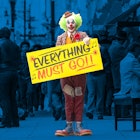 The Joker standing in a busy street holding a highlighted sign: "Everything Must Go"