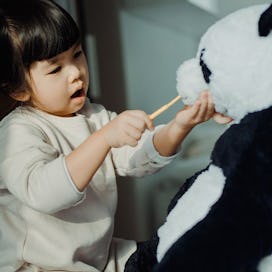 Toddler pretending her teddy is a patient.