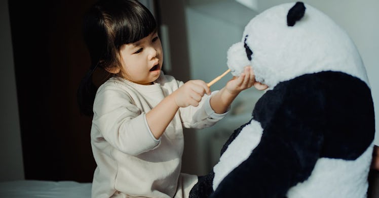 Toddler pretending her teddy is a patient.