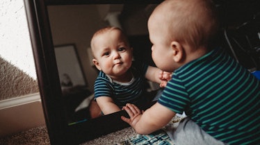 A baby looking itself in the mirror