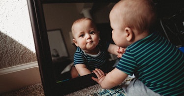 A baby looking itself in the mirror