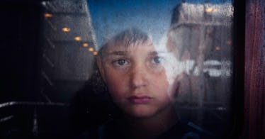 A sad boy whose father is deployed looking out of the window