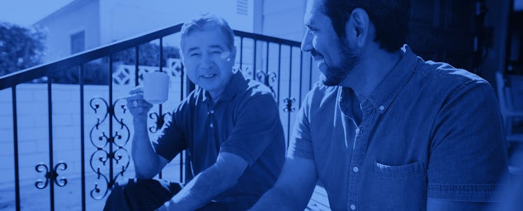 An older man and his grown sun on the front steps of their house, sharing a cup of coffee