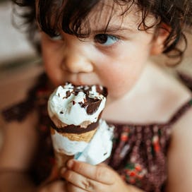 Toddler eating a dipped ice cream cone.