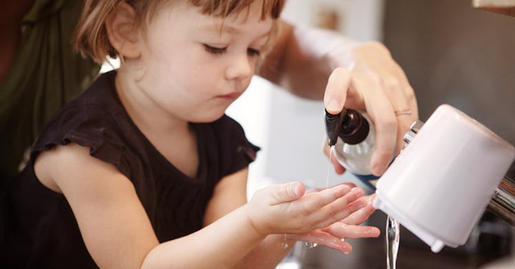 A parent helping their toddler wash her hands in the bathroom
