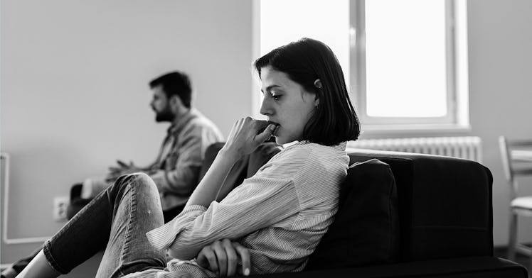 A husband and a wife sitting apart on a couch