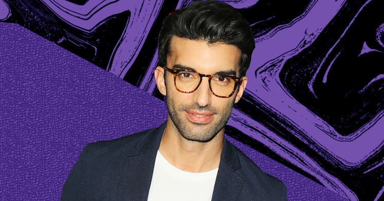 Justin Baldoni in a white shirt and black blazer wearing glasses with an abstract purple-black backg...