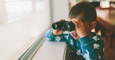 kid looking out window with binoculars