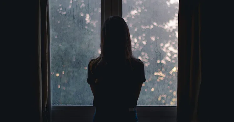 A child in shadow in front of a window.