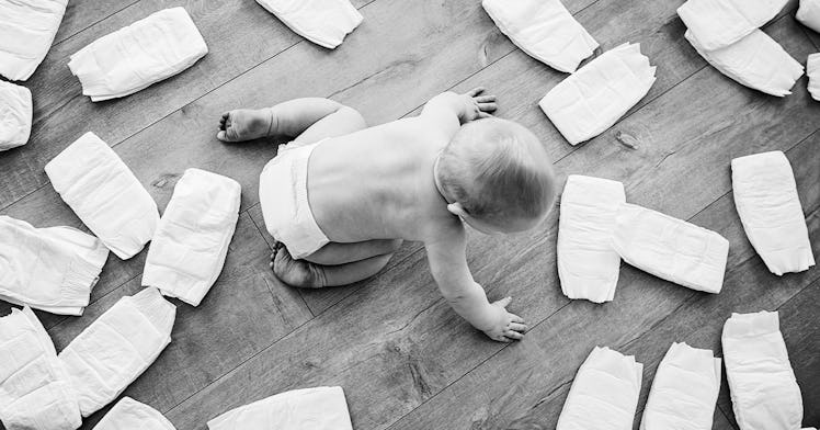Diapers surround a baby on the floor.
