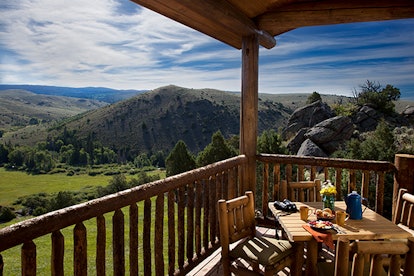 A dining table on the balcony of a Brush Creek Ranch room with a view on nature in Saratoga, WY 