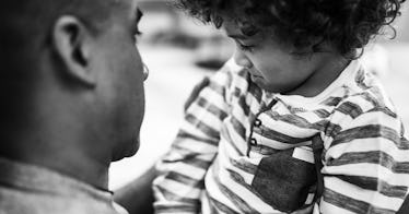 greyscale edit of dad holding 3 year old boy in striped shirt with curly hair practicing positive pa...