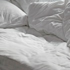 An unmade bed with white sheets.
