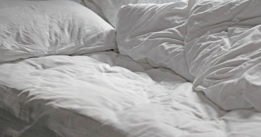 An unmade bed with white sheets.