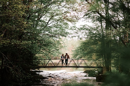 Two guests of Trout Point Lodge, Nova Scotia in Canada standing on a small bridge during their walk ...