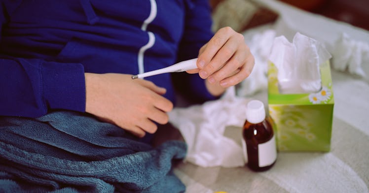 a person checks a thermometer to see if they have a fever