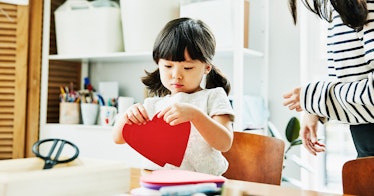 4-year-old girl cuts out a paper heart during craft activity