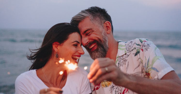 happy couple hold sparklers on beach