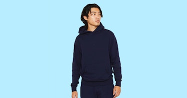 A model wearing Entireworld clothing, sweats and a hoodie, set against an aqua background