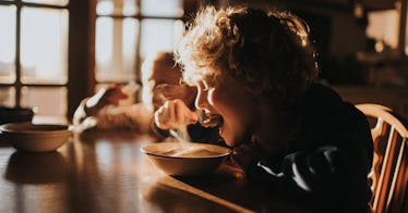 kid eats a bowl of food at table