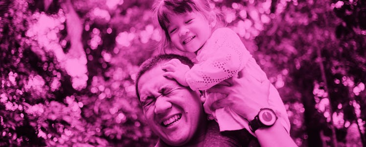 A father holding his daughter on the shoulders while they're both smiling