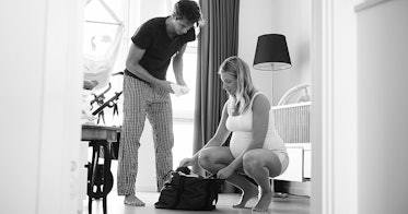 grey scale edit of a man holding forward a towel to a pregnant woman to place not a hospital bag