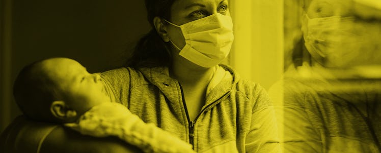 A mother holding her newborn baby while wearing a mask during the pandemic