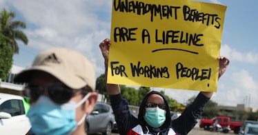 protestor carries a sign about unemployment benefits