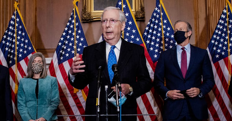 Mitch McConnell stands in front of flags