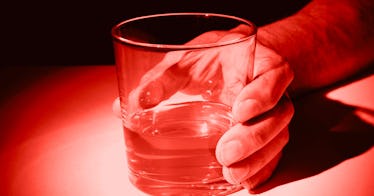 Red edit of a hand holding a glass of alcohol.