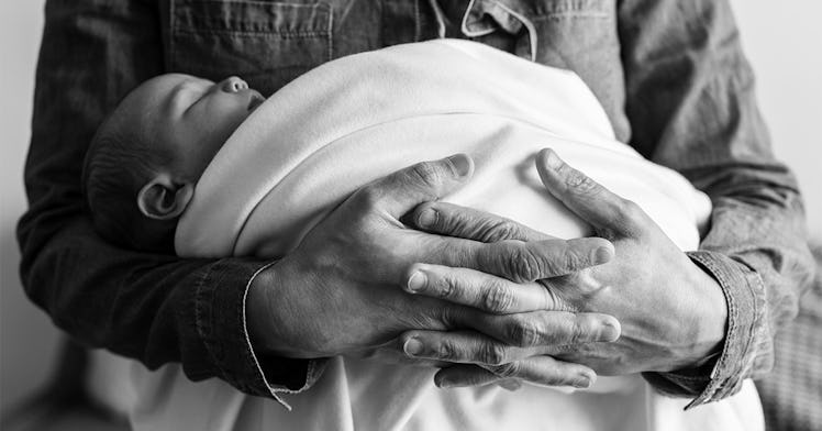 A baby is held in a blanket in black and white